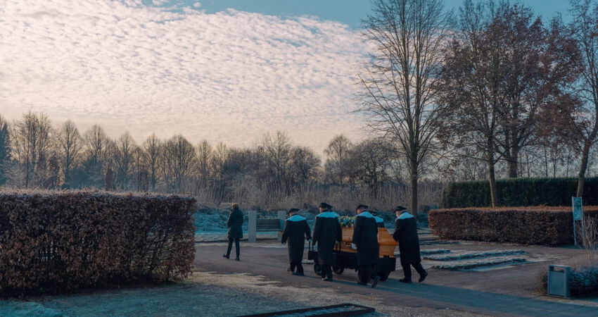 Sargträger bringen einen Sarg ans Grab